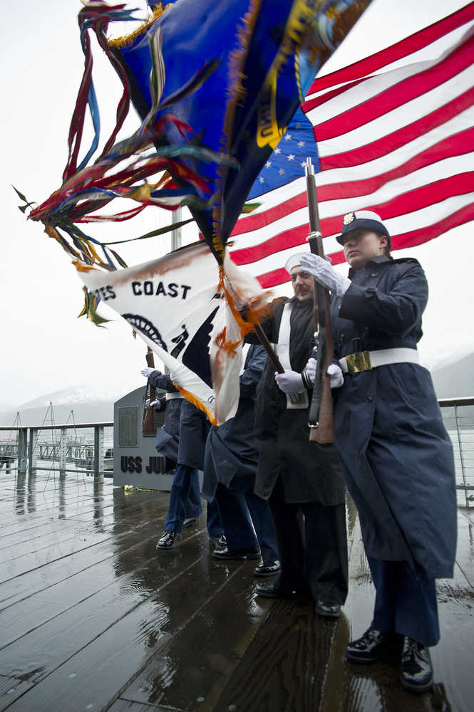 An honor guard made up of U.S. Coast Guard and Navy personnel struggle to hold their flags during wind gusts during a service at the U.S.S. Juneau Memorial downtown on Friday.