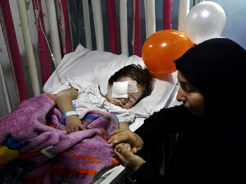 In this Nov. 13 photo, Adraa Taleb holds the hand of her maternal cousin Haidar Mustafa, three, who was wounded in Thursday's twin suicide bombings, as he sleeps on a bed at the Rasoul Aazam Hospital in Burj al-Barajneh, southern Beirut, Lebanon. Haidar's parents Hussein and Leila were killed in the blast as they were parking their car when one of two suicide attackers blew himself up in a southern Beirut suburb near their vehicle. Within hours of the Paris attacks last week that left 129 dead, outrage and sympathy flooded social media feeds and filled the airwaves.