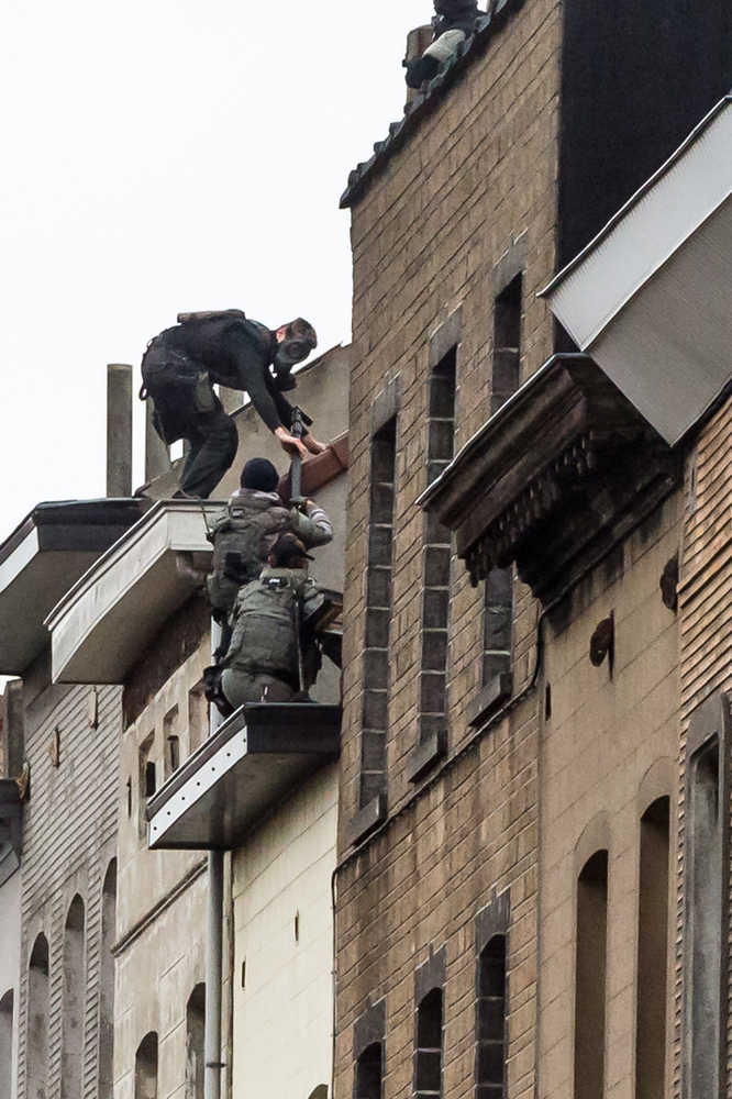 Special intervention forces climb on top of a roof as they prepare to enter a house in Brussels on Monday amid a manhunt for a suspect of the Paris terror attacks.