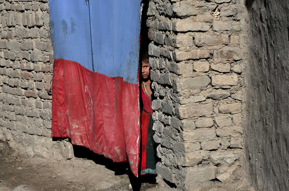 An Afghan refugee girl peers through the curtain of her temporary home on the outskirts of Kabul, Afghanistan, on Tuesday.