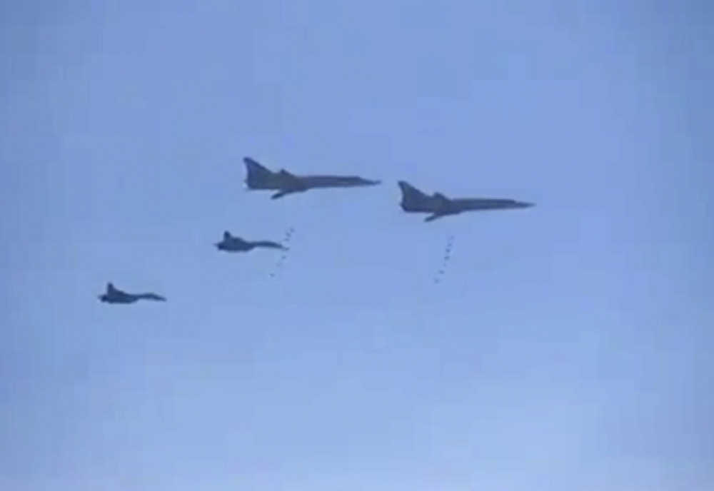 In this photo made from the footage taken from Russian Defense Ministry official web site on Tuesday, Russian Tu-22 bombers escorted by the Su-27s fighter jets drop bombs on a target in Syria.