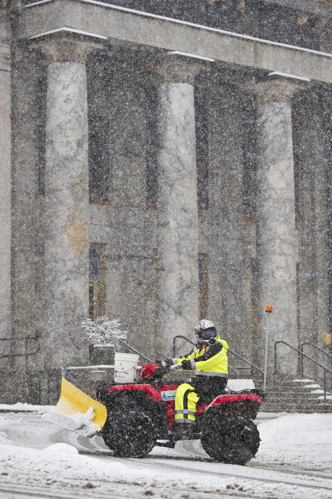 A city employee using a all-terrain vehicle passes by the Capitol building during Tuesday's snow showers.