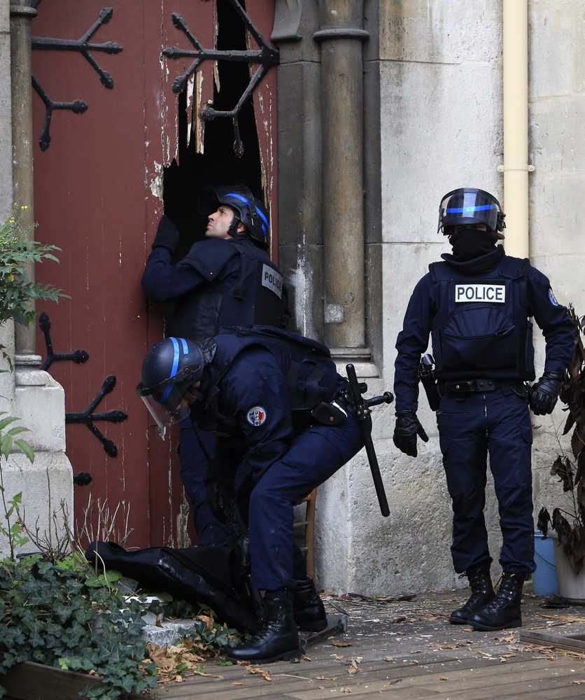 French police officers storm a church after a raid in Paris suburb Saint-Denis, Wednesday, Nov.18, 2015.  A woman wearing an explosive suicide vest blew herself up Wednesday as heavily armed police tried to storm a suburban Paris apartment where the suspected mastermind of last week's attacks was believed to be holed up, police said. (AP Photo/Thibault Camus)