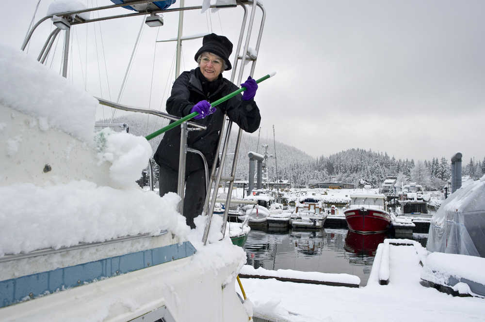 Gail Roust cleans snow off her boat docked at the Don Statter Memorial Boat Harbor in Auke Bay on Wednesday.