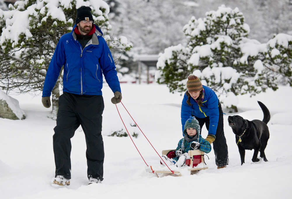 Matthew and Emily Thompson take their son, Juniper, 2, for a sled ride at Savikko Park on Thursday.