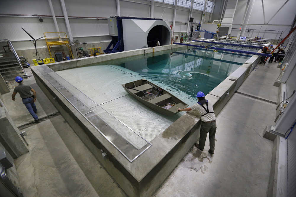 In this Nov. 20 photo, a technician steadies a skiff at the "beach" end in an indoor wave pool and wind tunnel at the University of Maine in Orono, Maine. The university's new 90-foot-long wind-wave basin is capable of simulating some of the worst conditions at sea at a 1:50 scale.