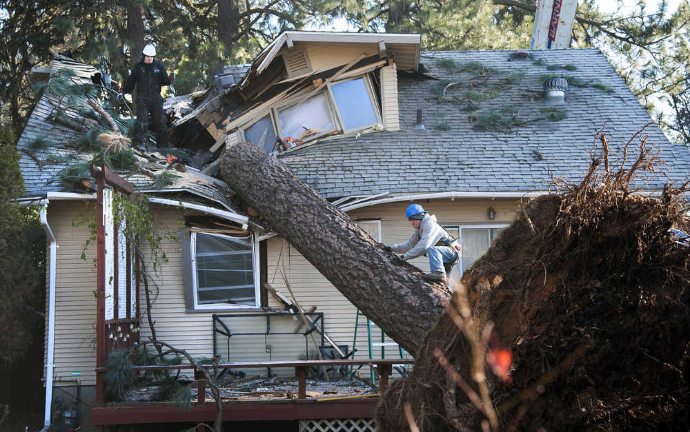 In this Nov. 21, 2015 photo, Jake Hines, left, and Ross Rukke, of Capstone Construction, work to remove a fallen tree in Spokane, Wash., after deadly storms swept through the state leaving many without power.  (Dan Pelle/The Spokesman-Review, via AP)