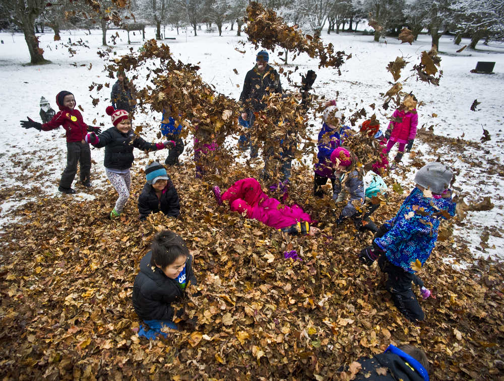 Second and third grade students from Harborview Elementary School frolic in a pile of dried leaves at Evergreen Cemetery on Tuesday. An annual event organized by Linda Torgerson, students from downtown schools collected, bagged and stored the leaves to be used on Monday and Tuesday.