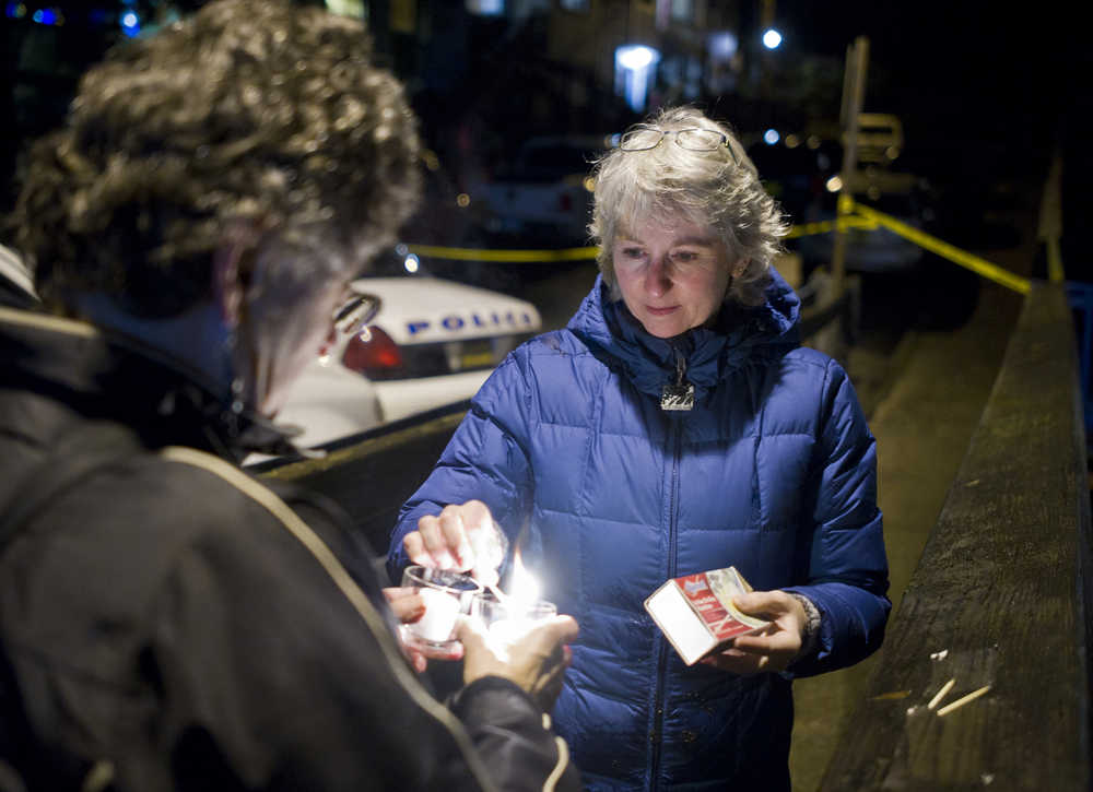DJ Thomson, right, and Joyce Levine light candles on Kennedy Street after hearing about the death of Mayor Greg Fish Monday evening.