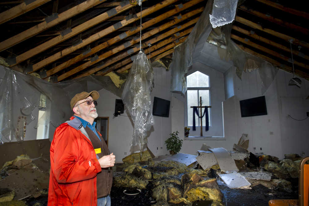 Deacon Larry Tong examines extensive interior damage to the main sanctuary at the Emmanuel Baptist Church on Wednesday. It appears the fire started in a vehicle outside the back wall of the church Tuesday night.