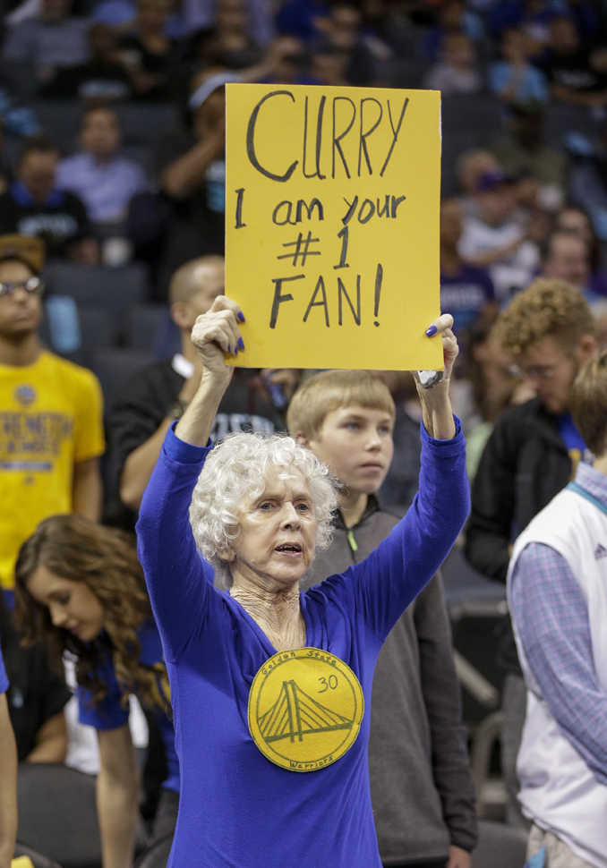 Diane Vixon holds a sign supporting Golden State Warriors guard Stephen Curry before an NBA  game against the Charlotte Hornets Wednesday.