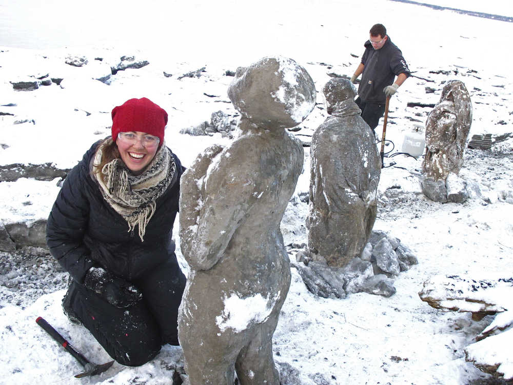 Lead project artist Sarah Davies poses by sculptures made of straw, cement, plaster and burlap that were damaged by incoming tides last week and were being repositioned Friday, Dec. 4, 2015, at the site of a public art installation in Anchorage, Alaska. Creators of the display plan to have the exhibit ready by Saturday for its official opening. Participants say the 100Stone project represents people dealing with emotional vulnerabilities, including trauma and mental illness. (AP Photo/Rachel D'Oro)