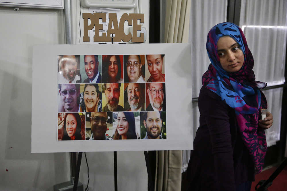 Dounia Omar, right, sets up a poster showing the photos of 14 people killed in Wednesday's shooting rampage before the start of a memorial service at the Islamic Community Center of Redlands on Sunday in Loma Linda, California.