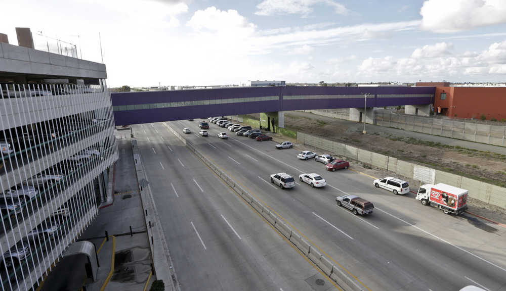 In this Nov. 25 photo taken in Tijuana, Mexico, vehicles pass under a walking bridge that connects the new Cross Border Xpress air terminal in San Diego, right, to the Tijuana International Airport, left. The new terminal is scheduled to begin operations on Wednesday.