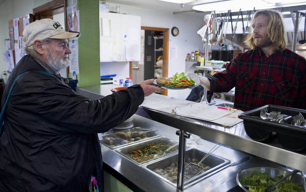 Facilities Coordinator Odin Miller, right, serves Mario Capolicchio lunch at The Glory Hole on Monday.