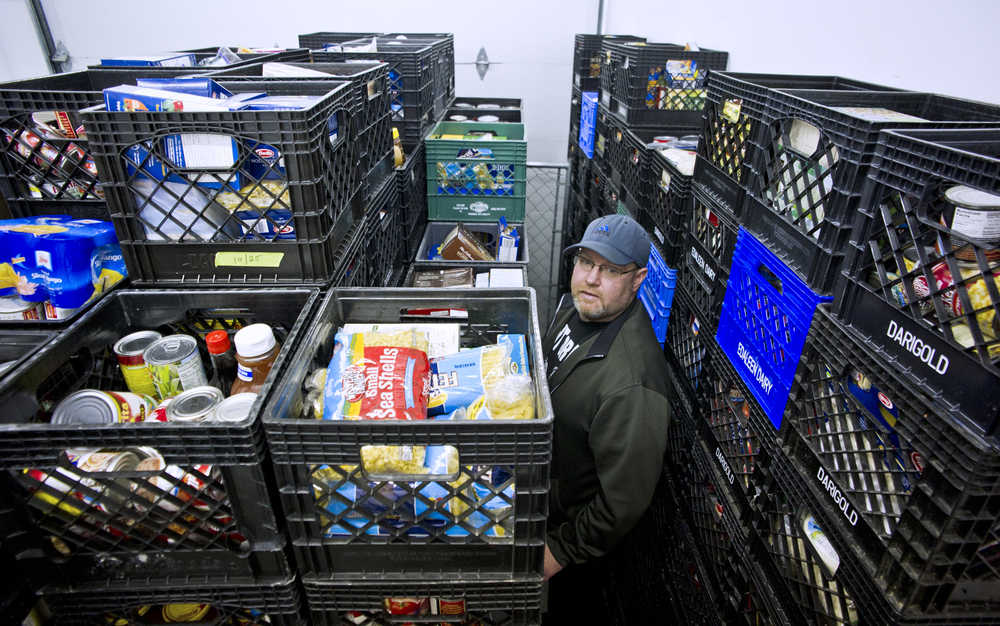 Darren Adams, manager of the Southeast Alaska Food Bank, stands next to donated food at their warehouse on Crazy Horse Drive on Tuesday. The food bank is building a new building next spring to provide more storage area.