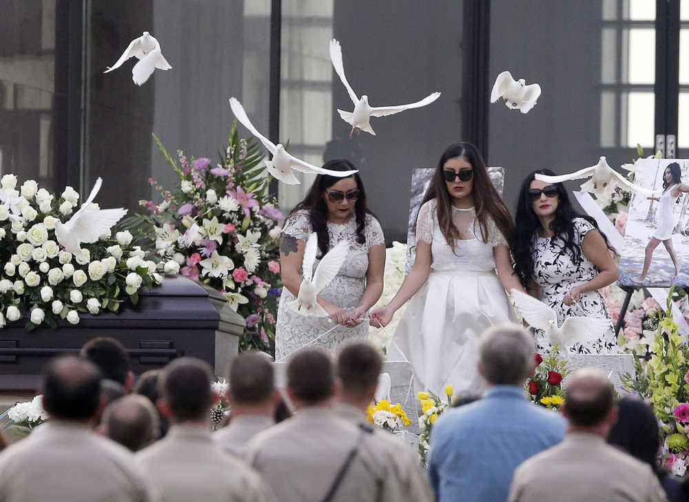 The sisters of Yvette Velasco release doves of during a memorial service on Thursday, Dec. 10, 2015 in Covina, Calif. Velasco died in a mass shooting in San Bernardino, Calif., that killed 14 and injured 21 last Wednesday. (AP Photo/Chris Carlson)