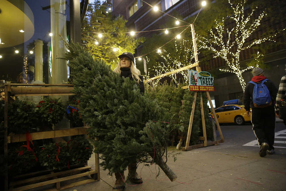 In this Dec. 8 photo, Laura Miller carries a tree she just sold at her Laura's Christmas Trees stand on the Upper West Side neighborhood of Manhattan in New York.
