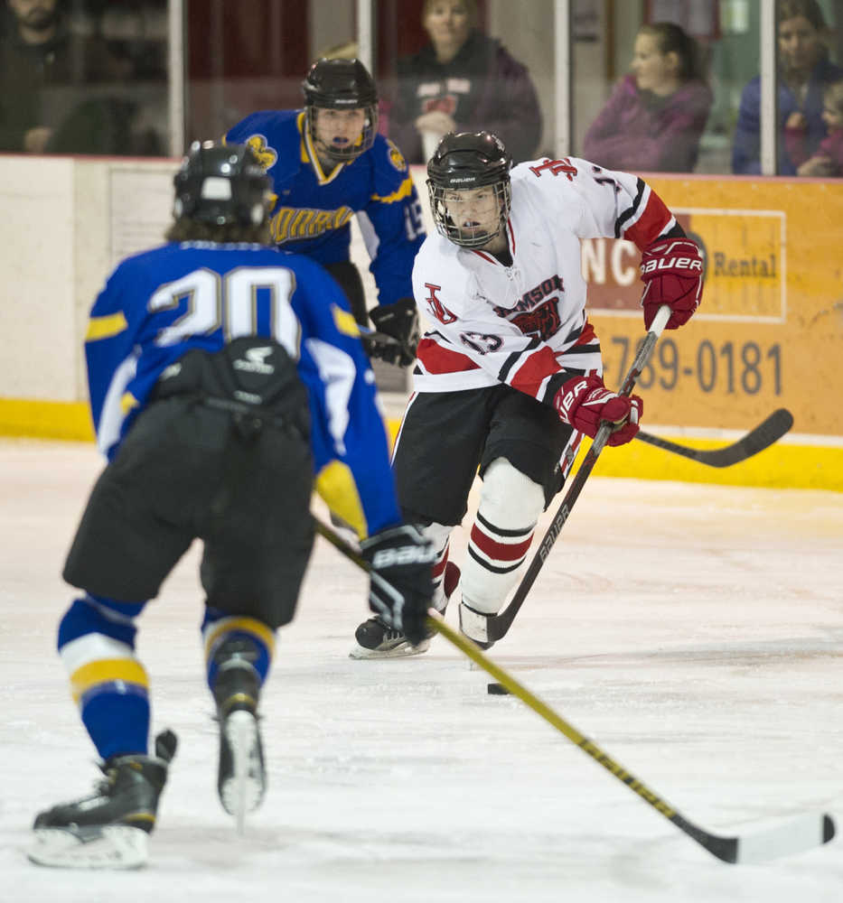 Juneau-Douglas' Jacob Dale, center, drives between Monroe Catholic's Bela Armstrong, foreground, and Grant Olson, background, at Treadwell Arena on Saturday. Monroe Catholic won 3-1.