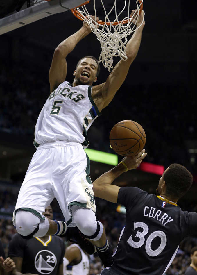 Milwaukee Bucks' Michael Carter-Williams dunks over Golden State Warriors' Stephen Curry Saturday.