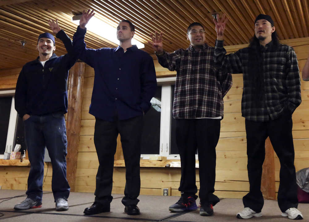 The Fairbanks Four - Marvin Roberts, left to right, Kevin Pease, Eugene Vent, and George Frese - hold up four fingers, symbolizing the Fairbanks Four, in the David Salmon Tribal Hall after they were freed on Thursday in Fairbanks.