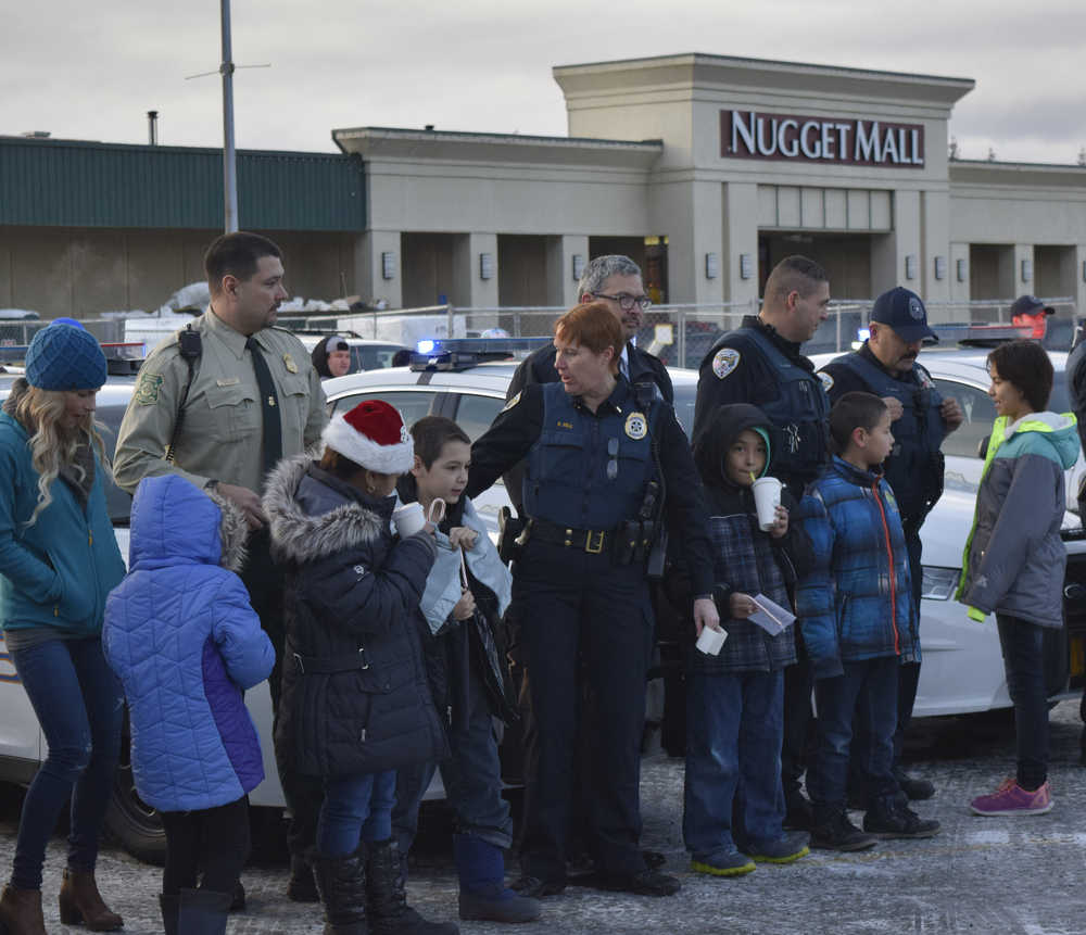 Law enforcement officials with the Juneau Police Department, Alaska State Troopers, Alaska Department of Corrections and U.S. Forest Service prepare to take local youth shopping in front of the Nugget Mall on Saturday.