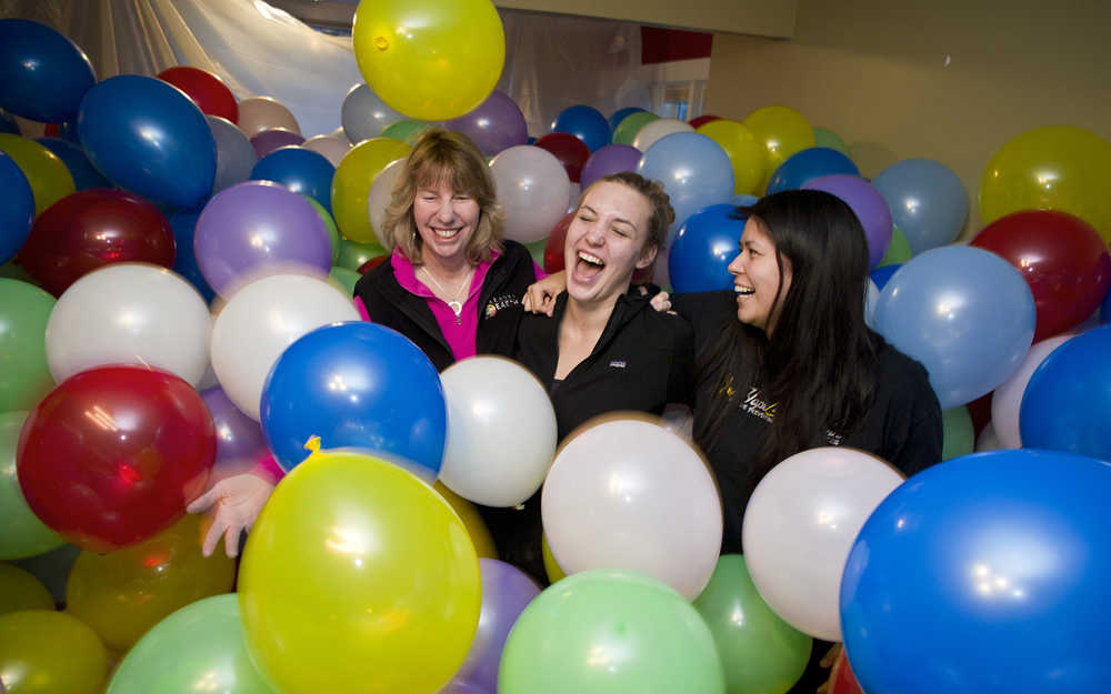 Rosanne Schmitz wades through nearly 2600 balloons with her daughter, Aileen, center, and friend, Tori Talley, right, in her livingroom on Monday. Schmitz tranformed her livingroom to celebrate her daughter's 21st birthday. Schmitz also opened her house to friends to frolic and ended it with a popping party Monday night.