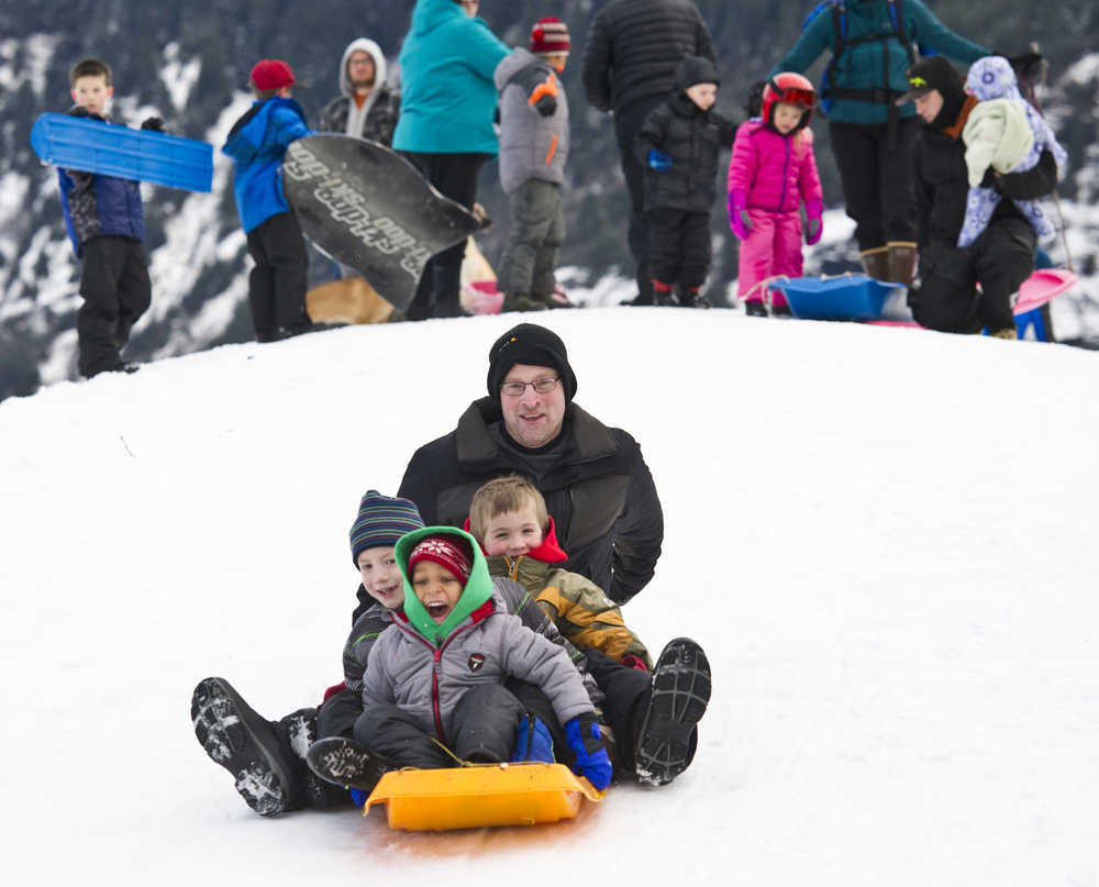 Geoffrey Wyatt sleds with his son, Lucas, 5, Orion Paden, 5, and Momar Diouf, 3, in front of the Mendenhall Glacier Visitors Center on Monday.