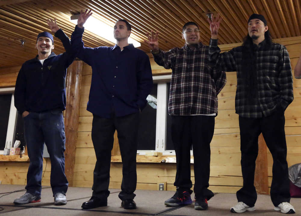 The Fairbanks Four - Marvin Roberts, left to right, Kevin Pease, Eugene Vent, and George Frese - hold up four fingers, symbolizing the Fairbanks Four, in the David Salmon Tribal Hall after they were freed on Thursday, Dec. 17, 2015 in Fairbanks, Alaska. A Superior Court Judge approved a settlement that threw out the indictments and murder convictions of the Fairbanks Four  in the 1997 death of teenager John Hartman.  (Erin Corneliussen/Fairbanks Daily News-Miner via AP)