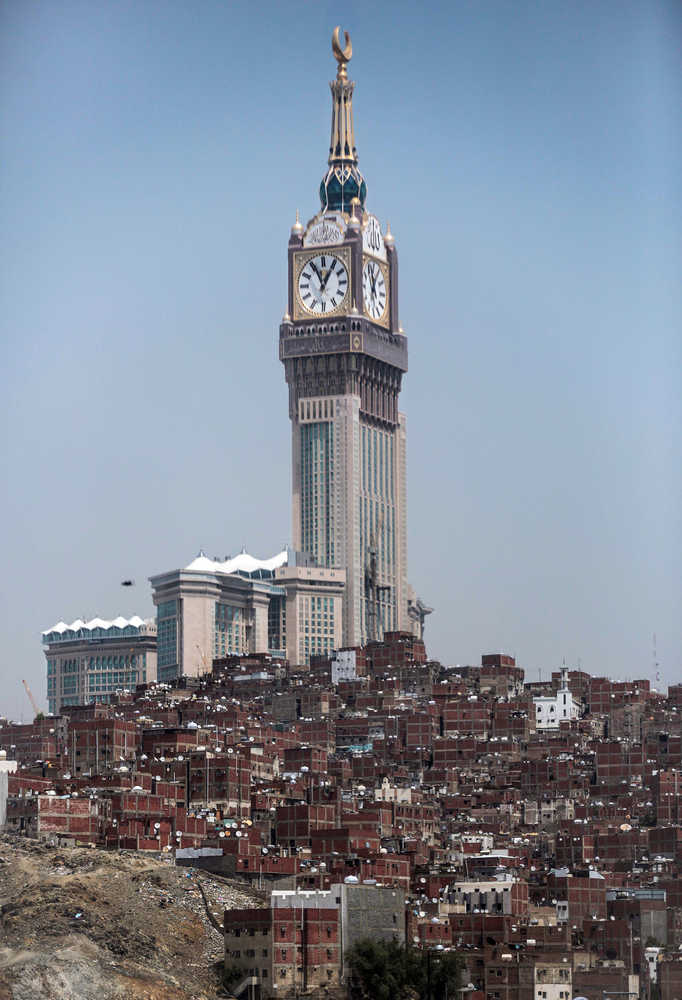 In this Sept. 17 photo, the tallest clock tower in the world with the world's largest clock face atop the Abraj Al-Bait Towers, overshadows mountain slums in the holy city of Mecca, Saudi Arabia. The kingdom has announced on Monday, a projected budget deficit in 2016 of $87 billion, as lower oil prices cut into the government's main source of revenue.