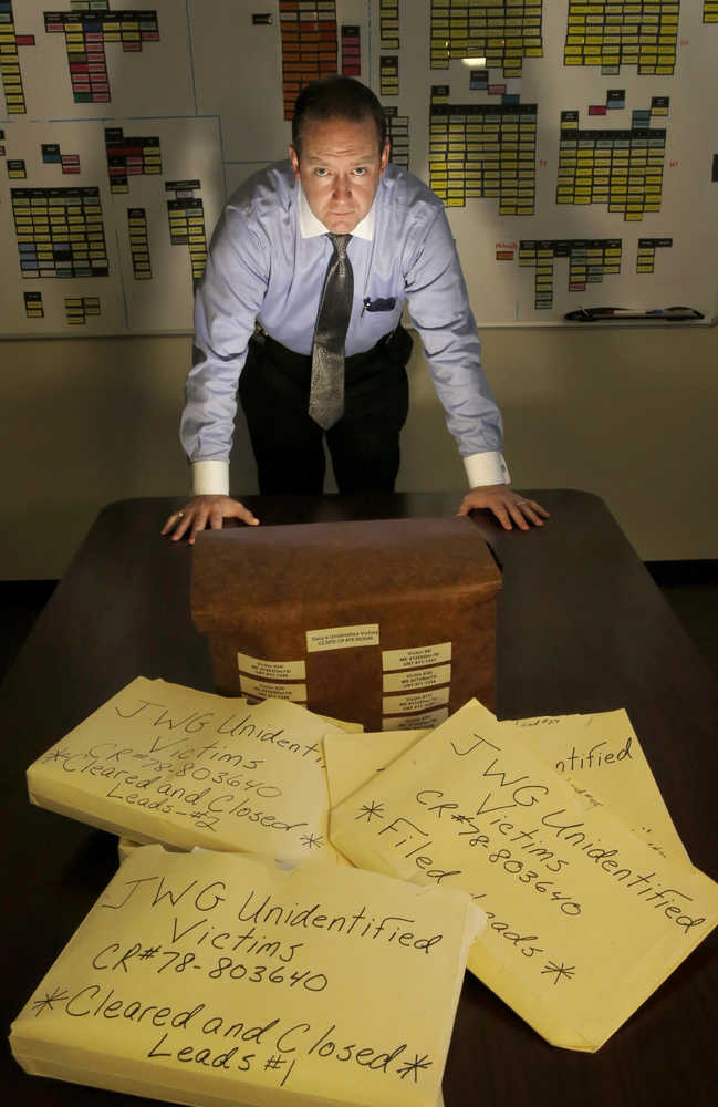 In this Dec. 3 photo, Cook County Sheriff's Detective Jason Moran poses for a portrait with his case files of unidentified victims of serial killer John Wayne Gacy in Maywood, Illinois. While working to identify these victims, Moran has cleared 11 cold cases across America that had nothing to do with Gacy.
