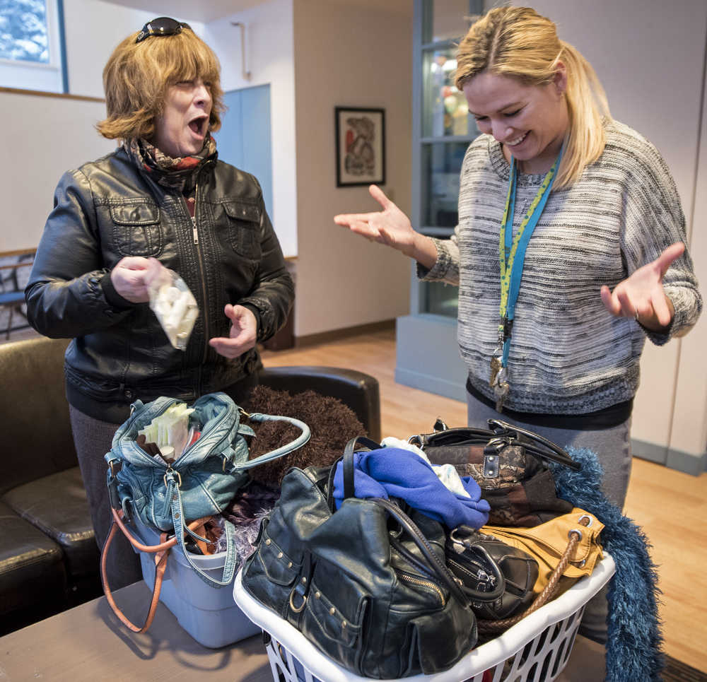 Suzanne Dutson, co-creator of the "Juneau Pay-it Forward" Facebook group, left, delivers 23 purses filled with toiletries, gloves, scarves and feminine hygiene products to Christina Love, an advocate for AWARE, at the AWARE shelter on Monday.