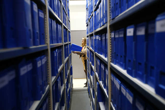 Pascale Etiennette, chief of the Paris Police Prefecture Archives department holds a file box in the controlled storage room where historic documents are stored in Paris, France, Tuesday.