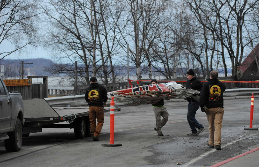 Workers load the remains of a small plane that crashed into two office building in downtown Anchorage onto a flatbed trailer on Tuesday.