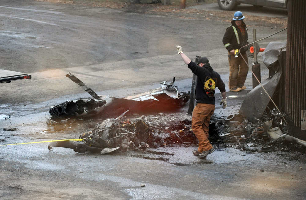 Workers load the remains of a small plane that crashed into two office building in downtown Anchorage on Tuesday.