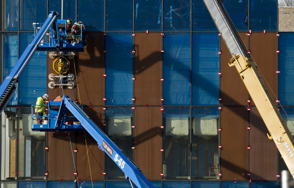 PCL Construction employees install panels onto the front of the State Library, Archives, and Museums building in October.