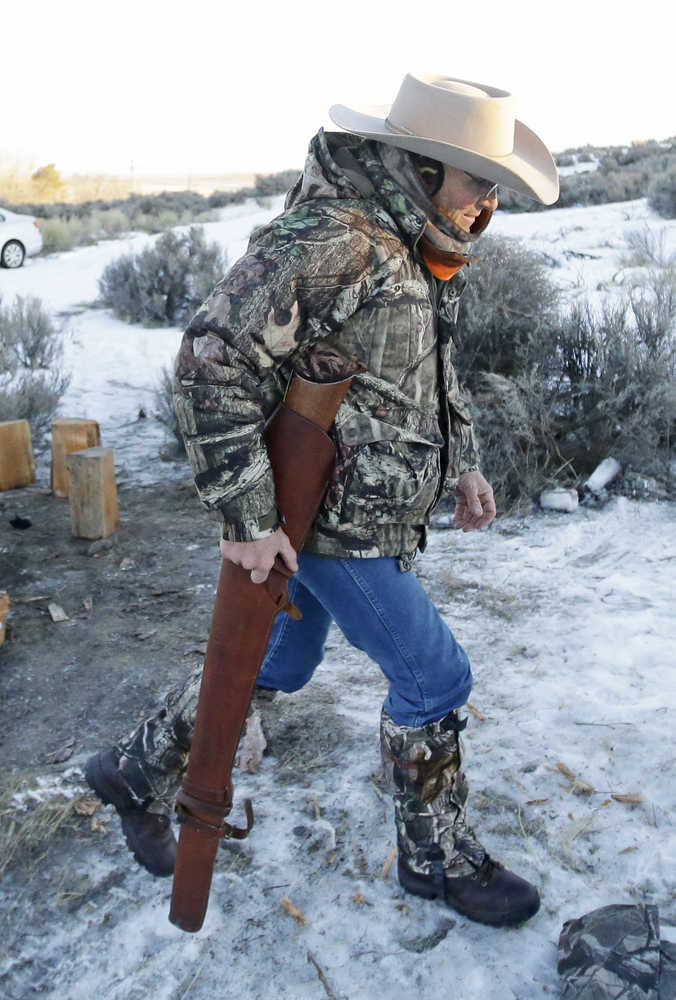 Arizona rancher LaVoy Finicum carries his rifle after standing guard all night at the Malheur National Wildlife Refuge, Wednesday, Jan. 6, 2016, near Burns, Ore. With the takeover entering its fourth day Wednesday, authorities had not removed the group of roughly 20 people from the Malheur National Wildlife Refuge in eastern Oregon's high desert country. But members of the group, some from as far away as Arizona and Michigan, were growing increasingly tense, saying they feared a federal raid. (AP photo/Rick Bowmer)