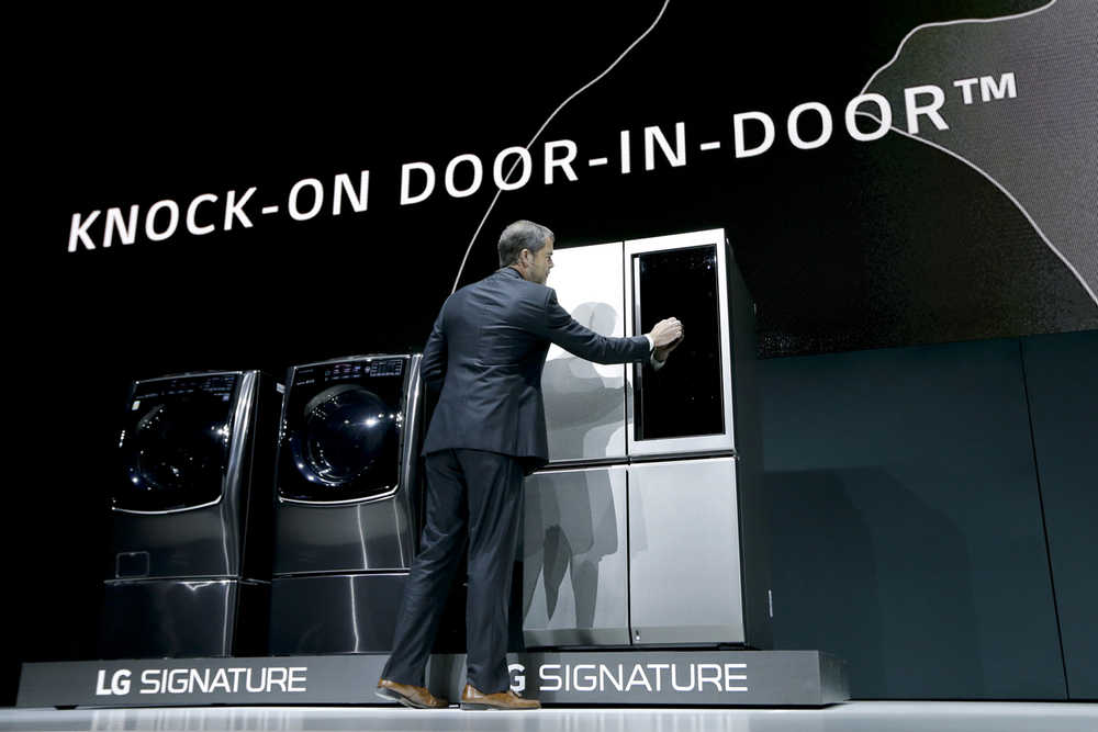 In this Tuesday photo, David VanderWaal, vice president of marketing for LG Electronics USA, knocks on the door of a new LG Signature refrigerator during a news conference preview for CES International in Las Vegas.