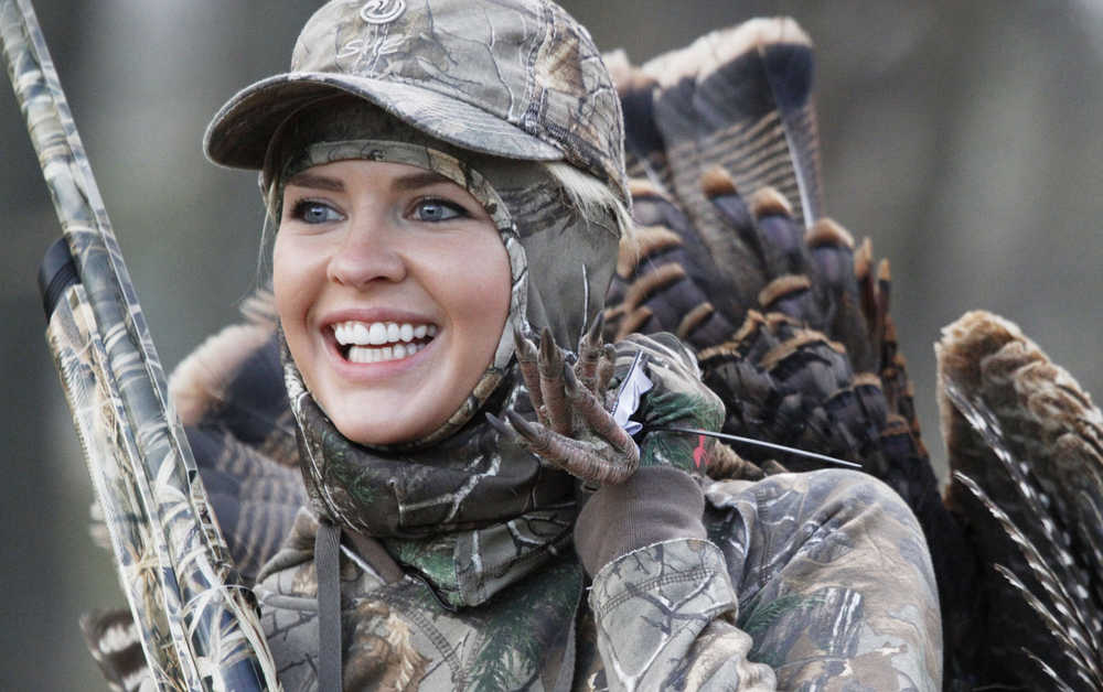 In this April 11, 2014 photo, Theresa Vail, a former beauty queen, holds a gun after shooting a turkey in Chase County, Kansas. Vail, who hosted an adventure TV show has pleaded guilty to killing an Alaska grizzly bear without a state tag. The sentence issued Wednesday includes one year of probation and a $750 fine.