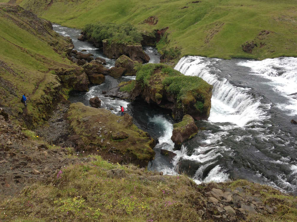 Hikers approach one of Icelands many waterfalls.