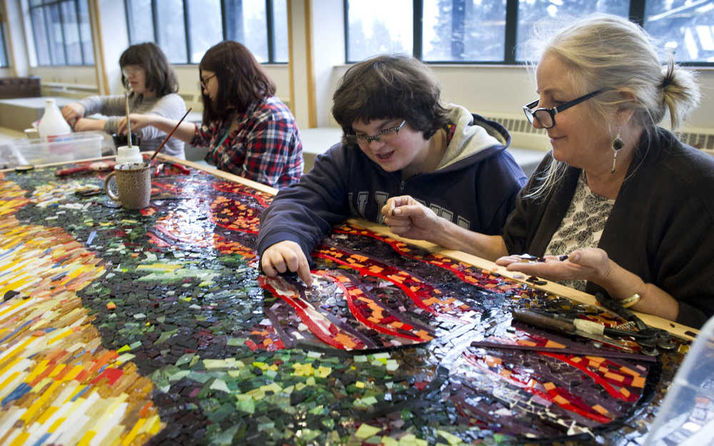 Artist Marianne Manning, right, works with seventh-graders Amanda Lamburt, center, Amy Budke and eighth-grader Claire Schumacker, left, on a three by eight-foot glass mosaic based on a painting by Dutch artist Vincent van Gogh at Dzantik'i Heeni Middle School on Wednesday. Manning is spending two weeks working with the middle school students on producing two glass mosaic panels as part of the Artist in the Schools Program.