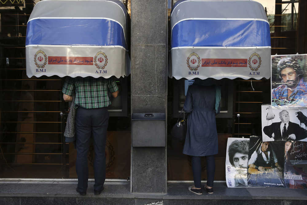 In this April 4, 2015 photo, Iranians use Bank Melli Iran ATMs in downtown Tehran, Iran.