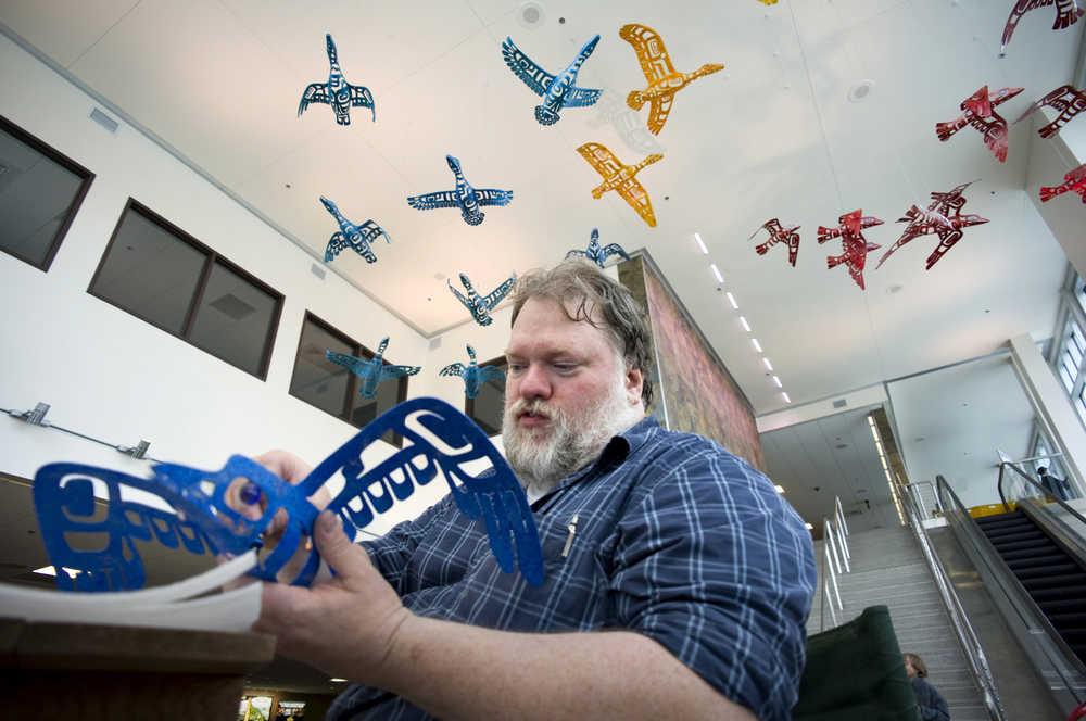 Steve Henrikson works to hang artwork created by him and his wife, Janice Criswell, in the Juneau International Airport in July 2011.
