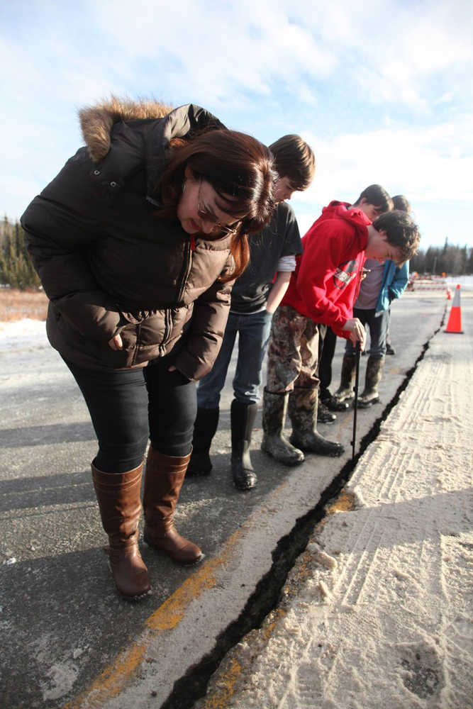 Stephanie Boyd, front, and her children assess a crack in the pavement of Kalifornsky-Beach Road following a magnitude-7.1 earthquake on Sunday near Kasilof.
