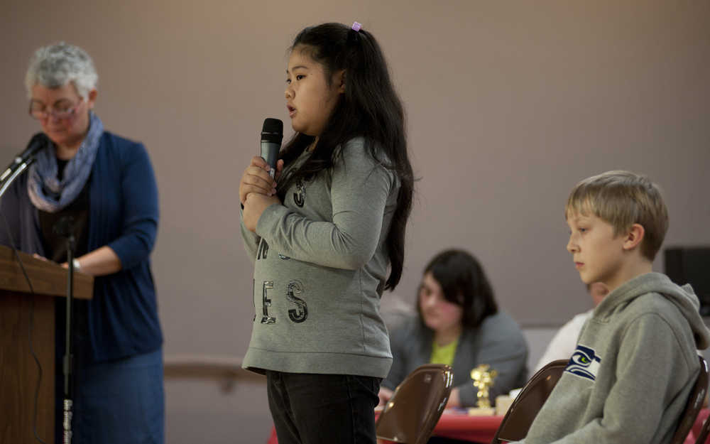 Keet Gooshi Heen Elementary School student Greisha Aviles, 9, correctly spells the word "udon" to win the school's spelling bee Tuesday Jan. 26, 2016,  in the multi-purpose room, as moderator Jacki Digennaro, at left, listens. James Helem, at right, finished second in the bee. Greisha will travel to Anchorage to compete in the state spelling bee. Eighth-grader Romy Bekeris won the Middle School spelling bee earlier this month, and will also compete at the state level. (Sentinel Photo by James Poulson)