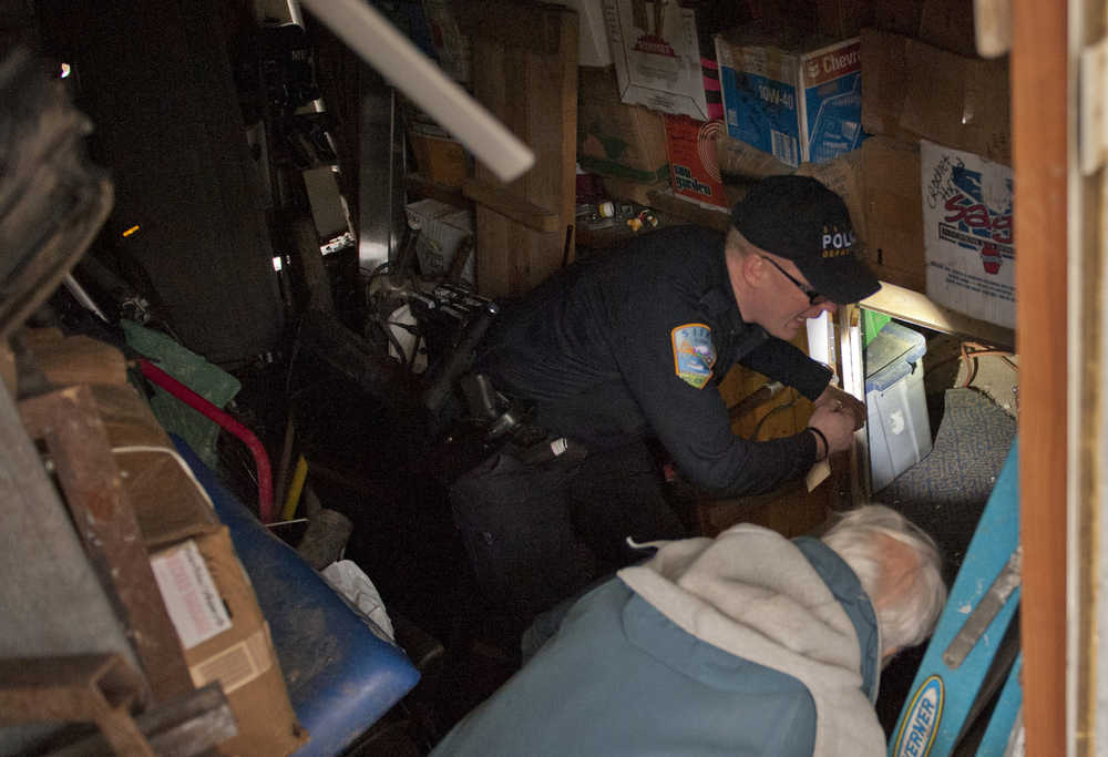 Sitka Police Lt. Lance Ewers shines a flashlight at the opening of a tunnel under a trailer in the Vitskari Trailer Park in Sitka, Alaska, Thursday, January 28, 2016, as he and the property's landlord, at right, inspect the property. A man wanted on criminal warrants was hiding under the trailer in what police called "an elaborate tunnel system." (AP Photo/Daily Sitka Sentinel, James Poulson)