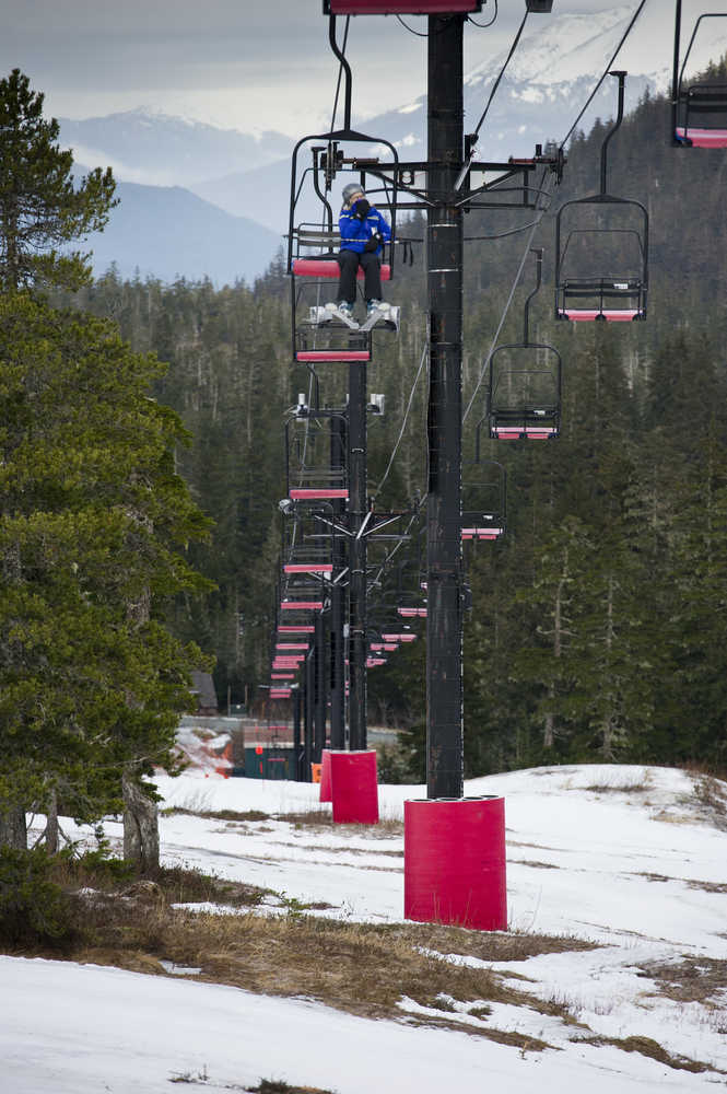 A skier rides the Hooter Chairlift over uncovered ground at the Eaglecrest Ski Area on Monday.