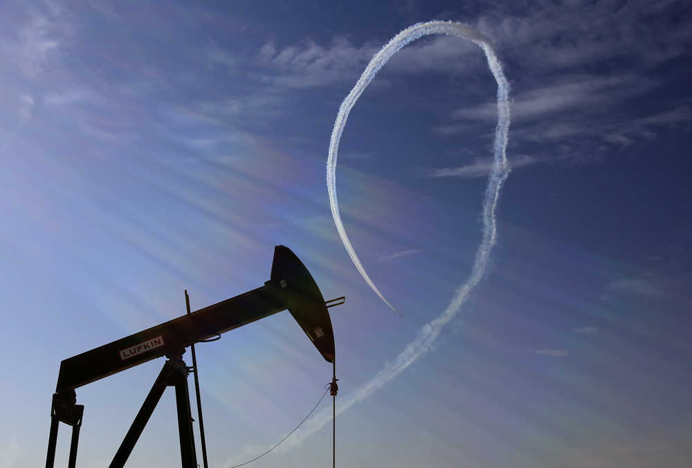 In this Jan. 23 photo, an oil pump stands as the Saudi Hawks Aerobatic Team of the Royal Saudi Air Force performs during the Bahrain International Airshow in Sakhir, Bahrain.