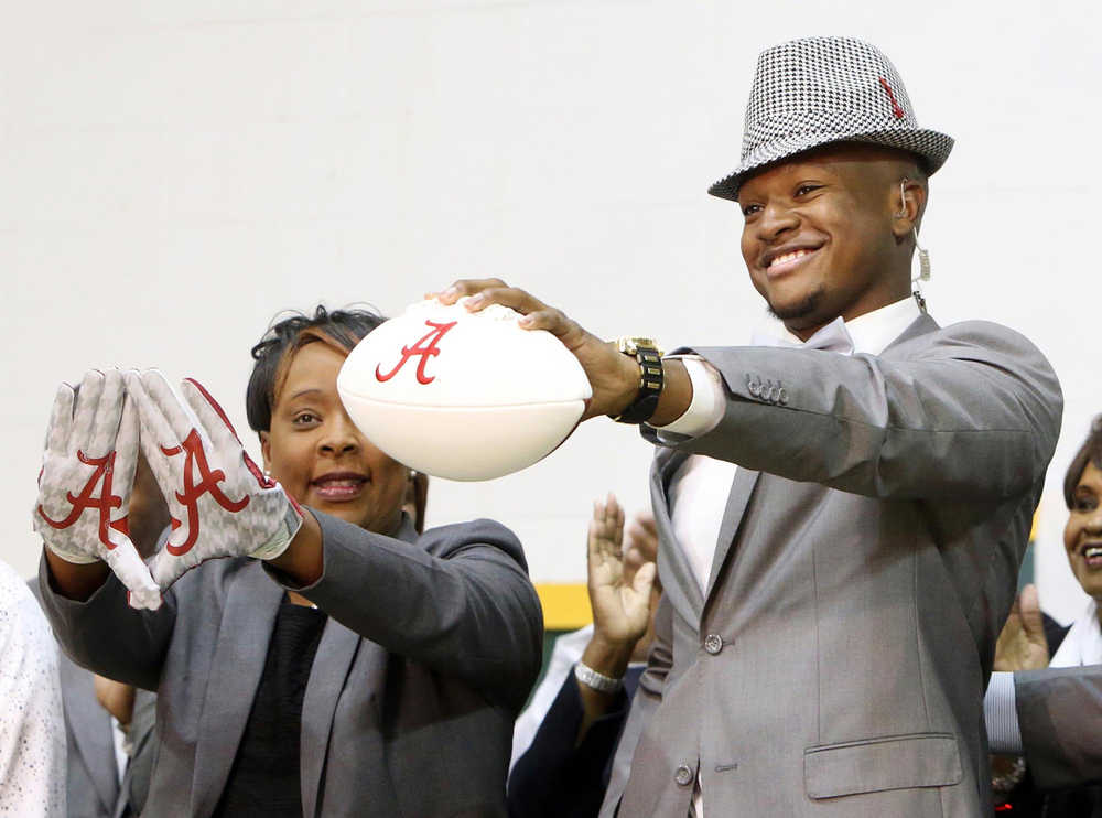 Gordo High School football player Ben Davis, with his mother Faye, left, holds up a football after committing to attend Alabama during a national signing day program at Gordo High School on Wednesday in Tuscaloosa, Alabama.