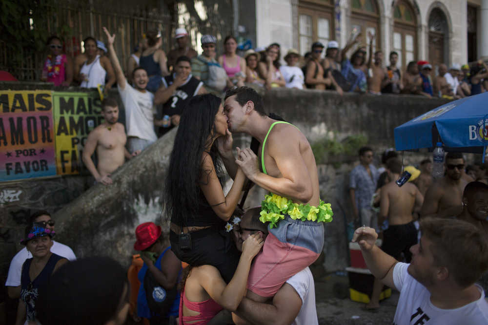 A couple kisses during the "Carmelitas" block party, during Carnival celebrations in Rio de Janeiro, Brazil, Friday, Feb. 5, 2016. Top Brazilian Health officials said this Friday that the active Zika virus has been found in urine and saliva samples, cautioning that further study is needed to determine whether the mosquito-borne virus in those body fluids is capable of infecting people. (AP Photo/Leo Correa)